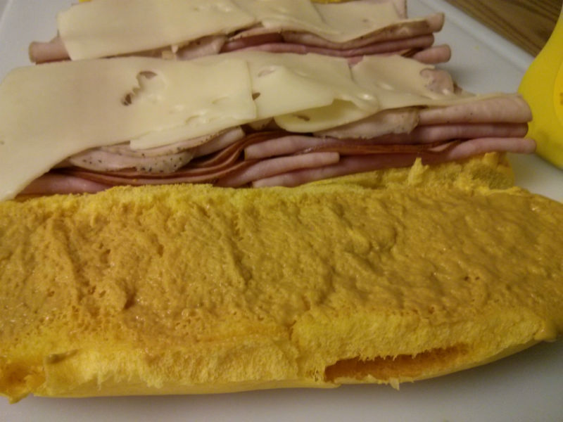 Medianoche bread with mustard and ham, pork and cheese piled high